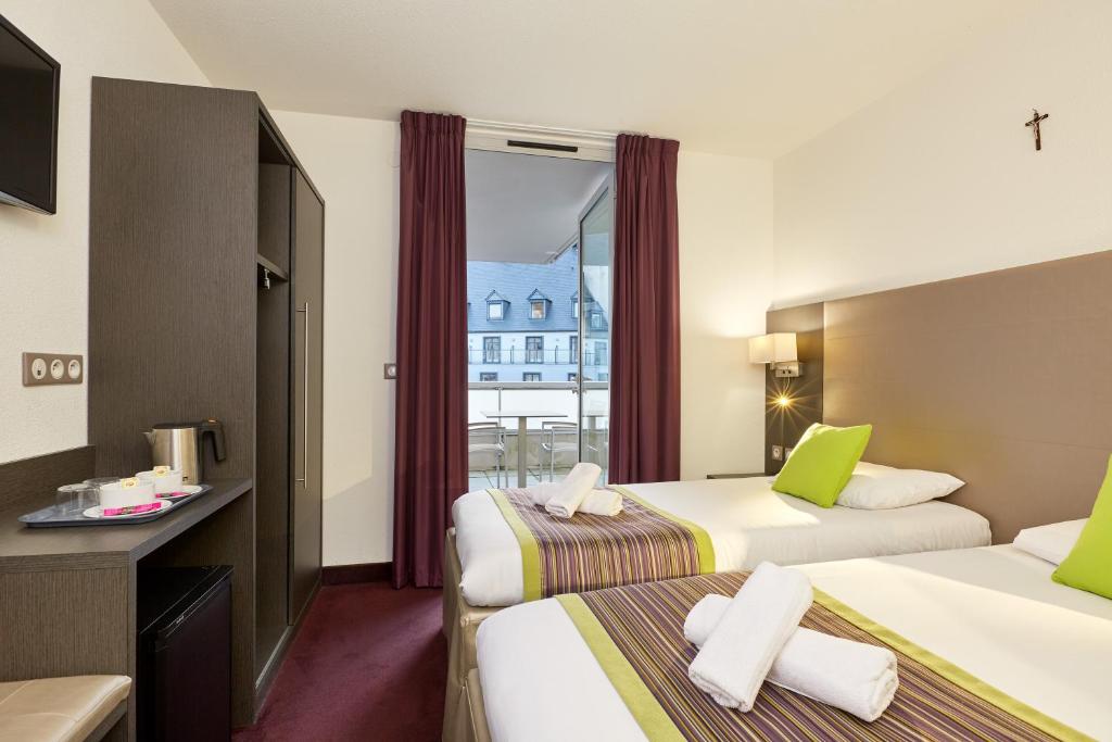 a hotel room with two beds and a balcony at Hôtel Astrid in Lourdes