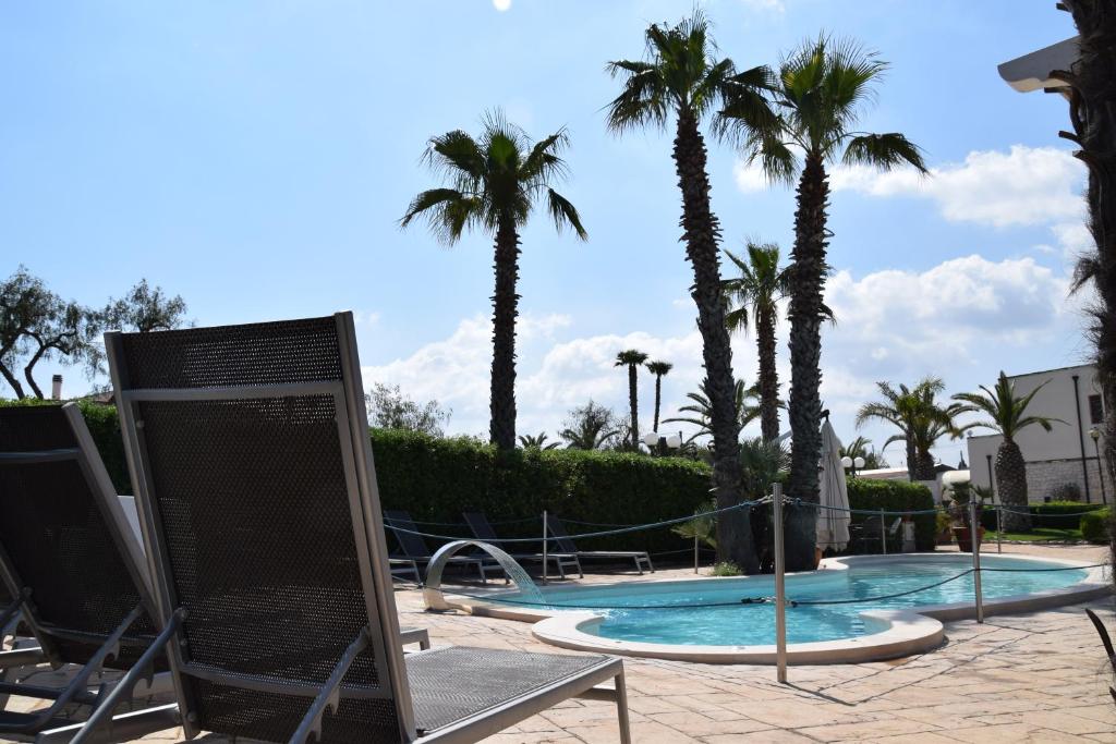- une piscine bordée de chaises et de palmiers dans l'établissement Masseria Casale Dei Fornici, à Polignano a Mare