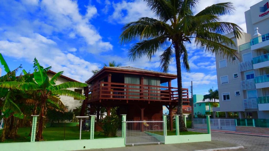 ein Gebäude mit einem Balkon neben einer Palme in der Unterkunft Bangalô com vista para o mar. in Governador Celso Ramos