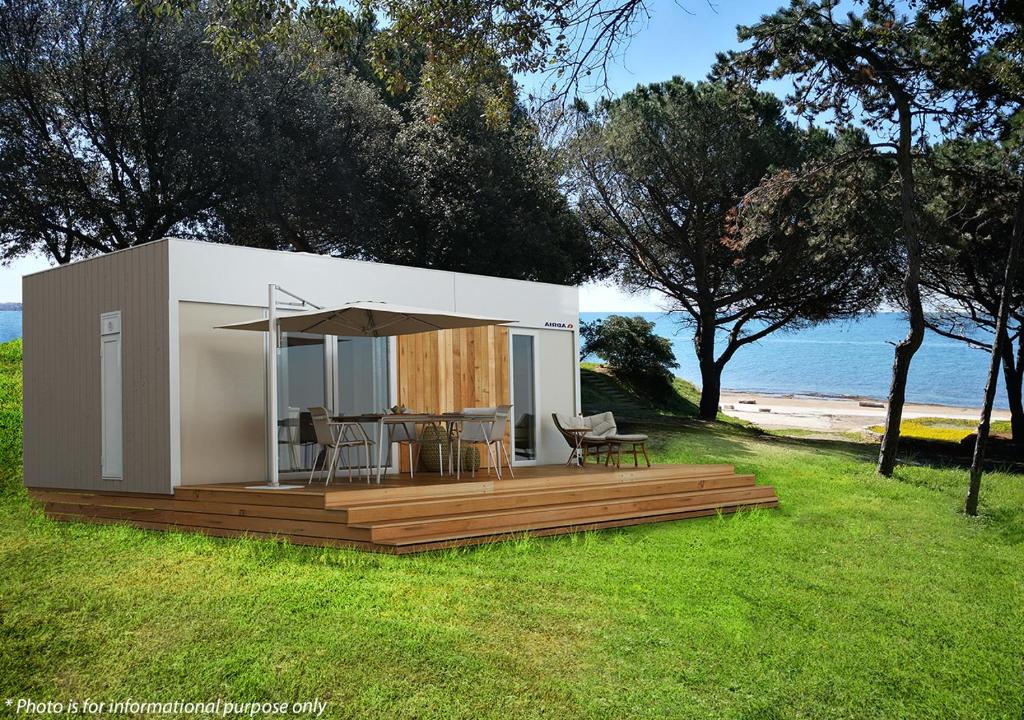 a small house with a deck and a table at Camping Home Adriamar in Novigrad Istria