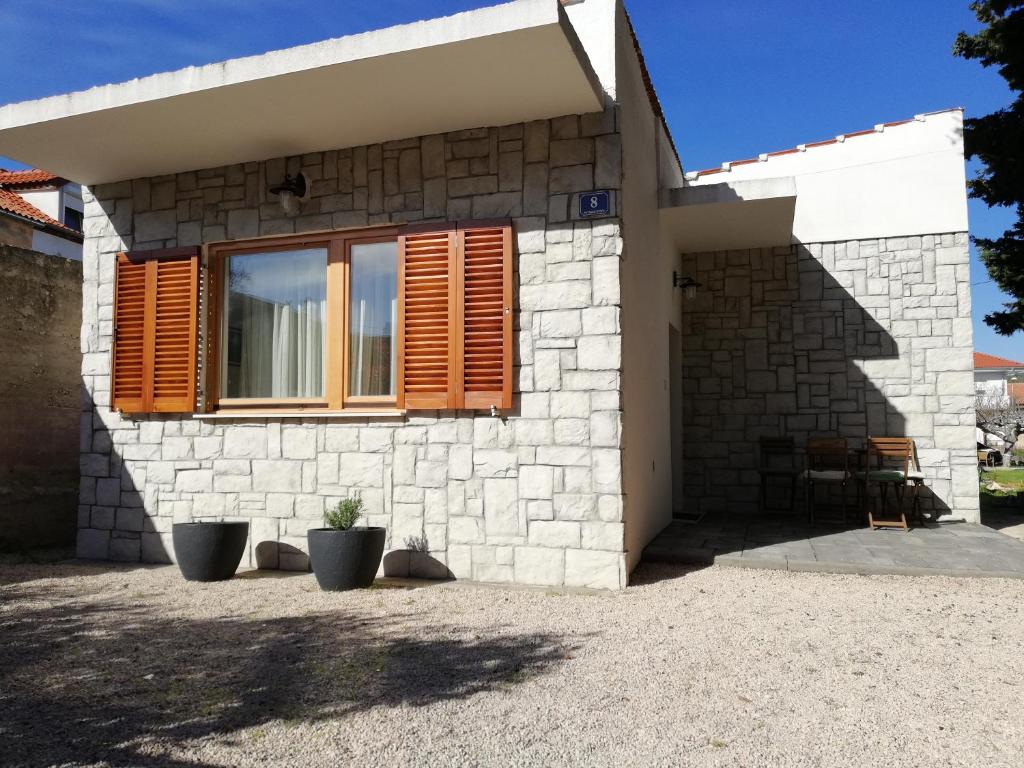 a brick house with a window and two plants at Kod Male Gospe in Tribunj