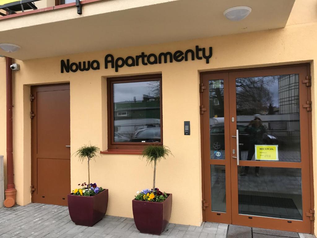 a nouvo apartments building with two plants in front of a door at Nowa Apartamenty in Krynica Morska