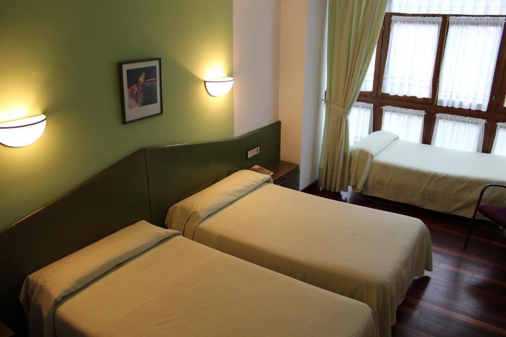 a hotel room with two beds and a window at Hotel Sindika in Oñati