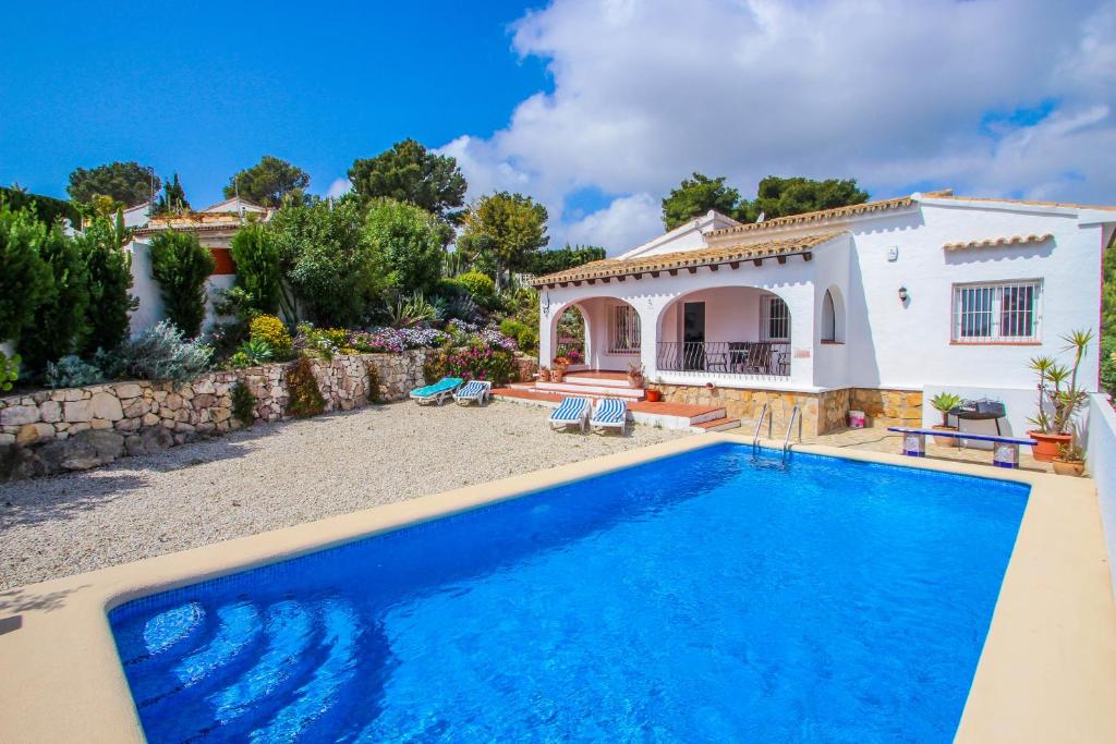 a villa with a swimming pool in front of a house at Susana - this lovely detached holiday property in Moraira in Moraira
