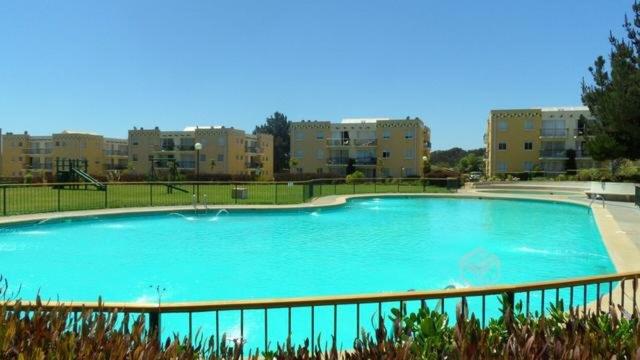 a large blue pool with buildings in the background at Depto Quisco Norte in El Quisco