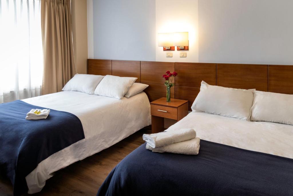 a hotel room with two beds and a vase of flowers at Filatelia Suites & Travel in Quito