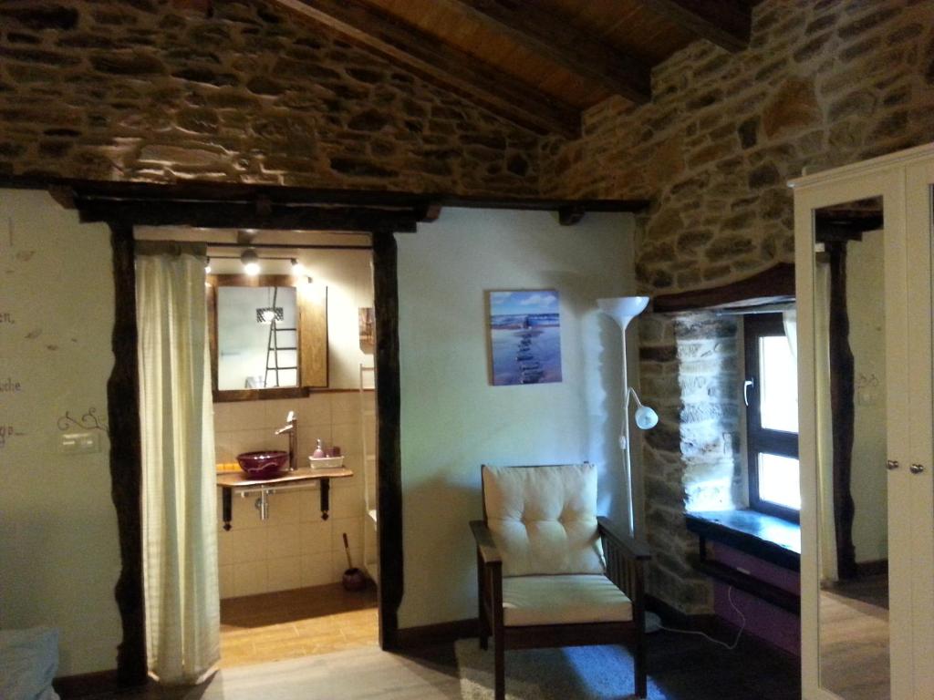 - un salon avec une chaise et un mur en pierre dans l'établissement CASA RURAL Calma del Lago, à Triufé