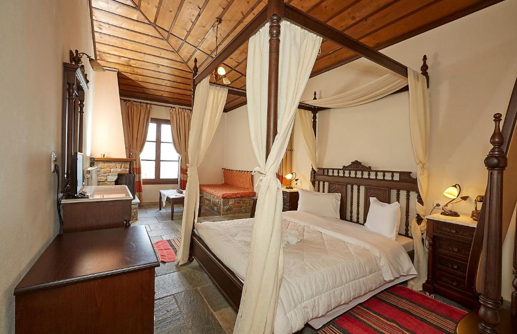 a bedroom with a canopy bed with a desk and a chair at Hotel Atrapos in Kissós