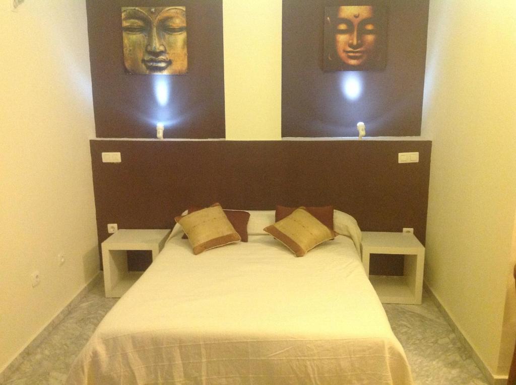 1 dormitorio con 1 cama con 2 máscaras en la pared en Hostal Neptuno, en Cáceres