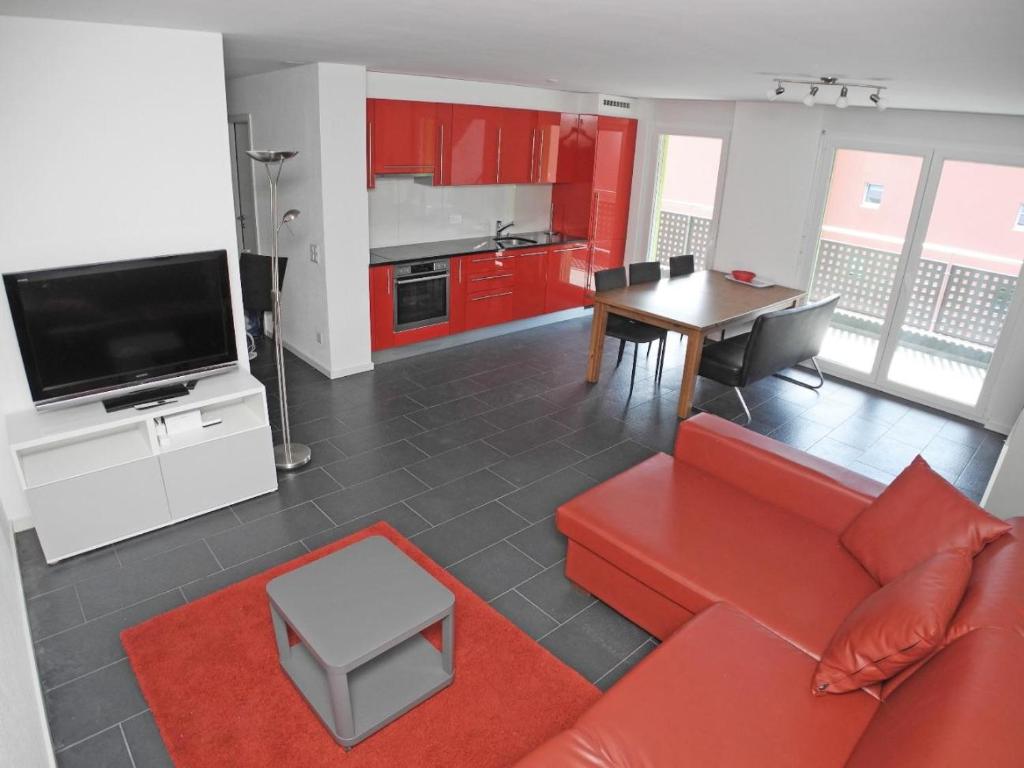 ein Wohnzimmer mit einem roten Sofa und einem Tisch in der Unterkunft Casa Jorio App 9999 in Locarno