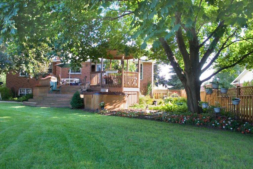 un patio con una casa con un árbol y una valla en A Li'l Bit of Eden en Niagara on the Lake