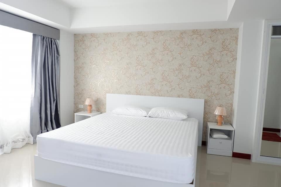 a white bedroom with a large white bed with two pillows at Phimai Residence in Phimai