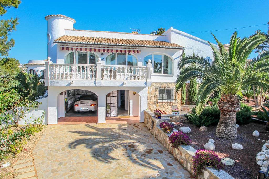 モライラにあるSusi - holiday home with private swimming pool in Morairaのバルコニーと私道付きの白い家
