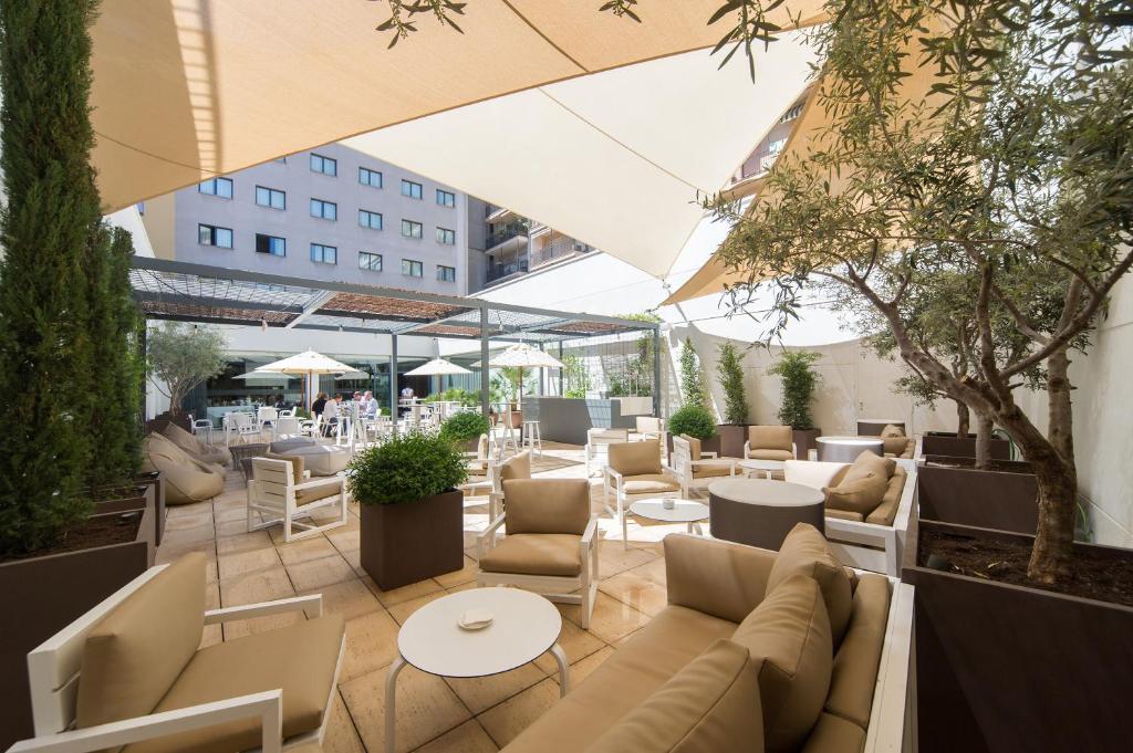 un patio con sofás, mesas y sillas en Hotel Vilamarí, en Barcelona