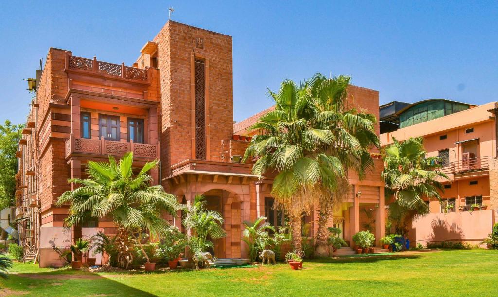a building with palm trees in front of it at Treebo Trend The Marwar Hotel & Gardens in Jodhpur