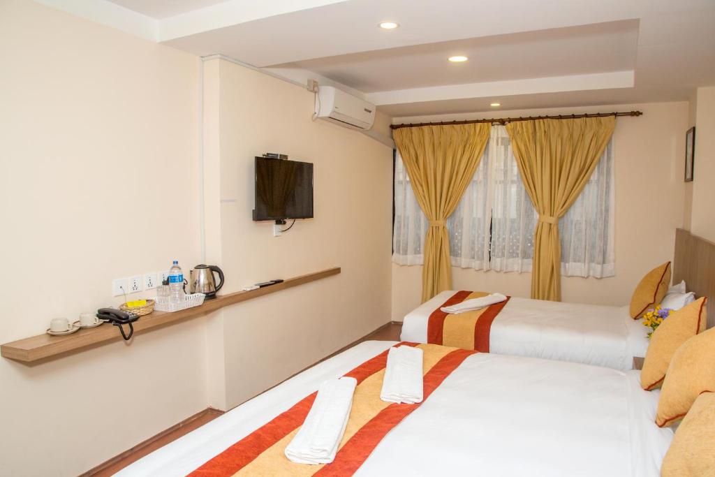 a hotel room with two beds and a tv at Sakura Boutique Hotel in Kathmandu