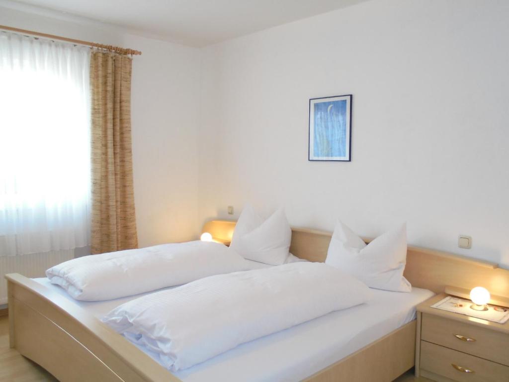 Cama blanca con almohadas blancas y ventana en Pension-Allendorf, en Oestrich-Winkel