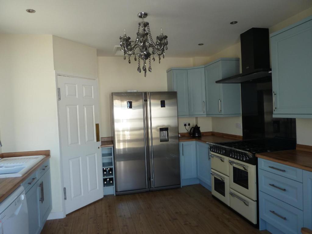 a kitchen with a stainless steel refrigerator and a chandelier at Captains Lodge in Newbiggin-by-the-Sea