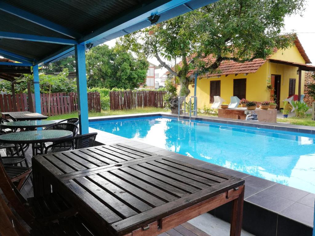 a swimming pool with a wooden bench next to a table at Coco Country Homes in Melaka