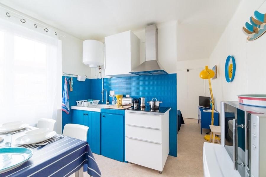 a blue kitchen with white cabinets and blue walls at Le Studio Bleu de la gare in Vieux-Boucau-les-Bains