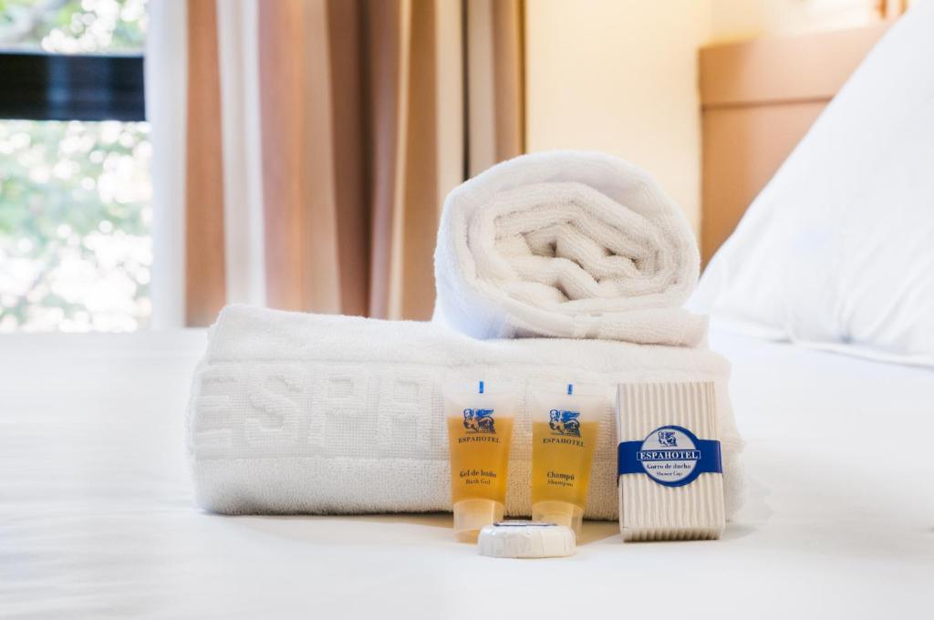 a pile of towels and toiletries on a bed at Espahotel Plaza Basílica in Madrid
