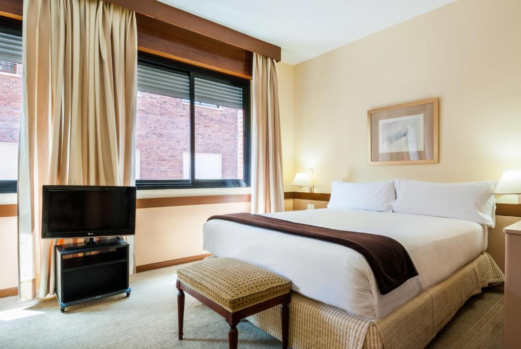 a hotel room with a bed and a television at Espahotel Plaza Basílica in Madrid