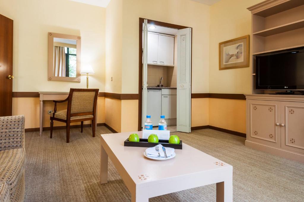 a living room with a coffee table and a kitchen at Espahotel Plaza Basílica in Madrid