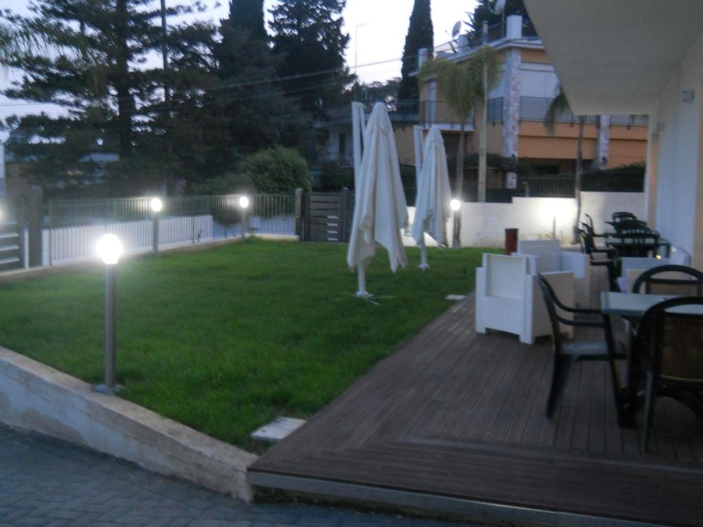 a patio with tables and white umbrellas on a lawn at Summer Beach Rooms in Fontane Bianche