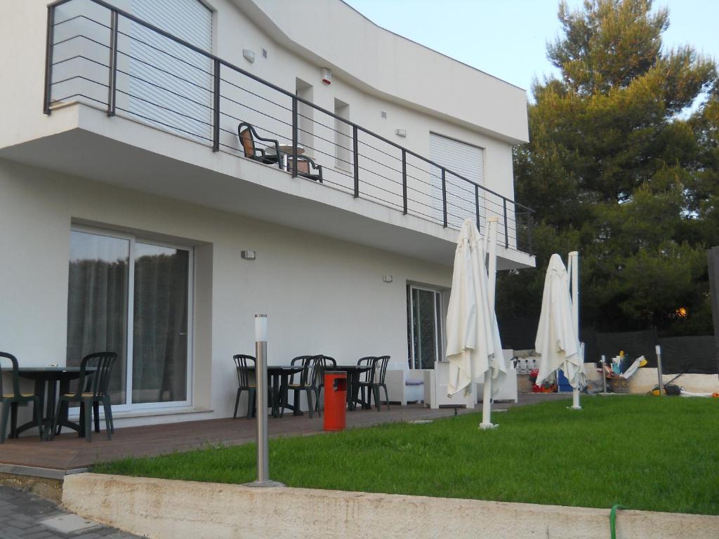 a house with a balcony with tables and umbrellas at Summer Beach Rooms in Fontane Bianche