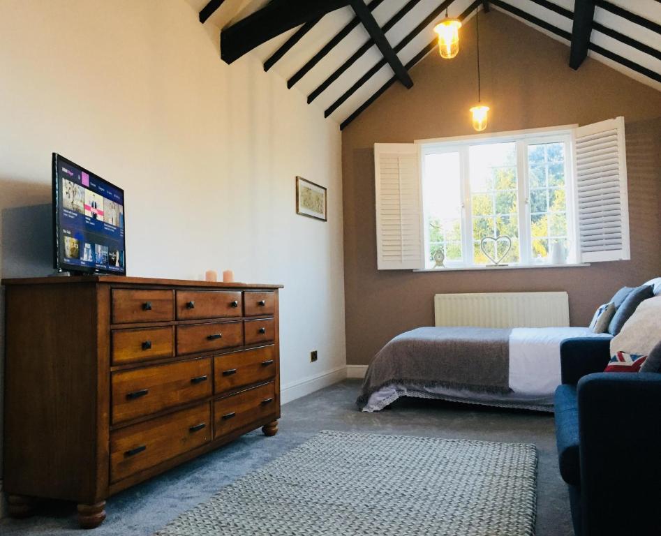 a bedroom with a bed and a dresser with a television at Kenilworth Cosy Garden View Apartment in Kenilworth