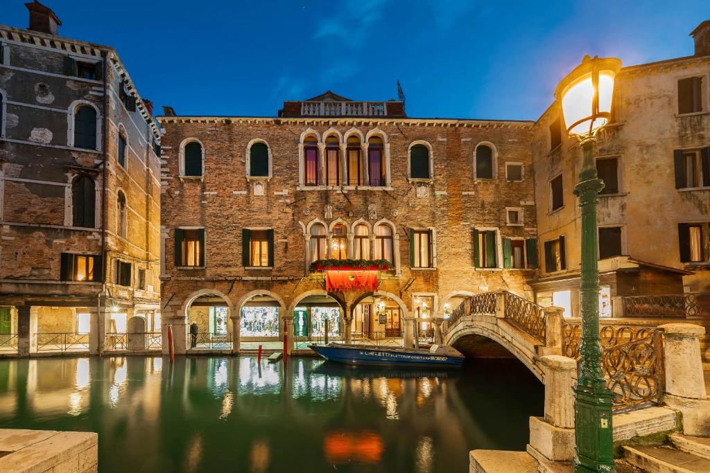 a canal in a city with a bridge and a boat at Hotel Antico Doge - a Member of Elizabeth Hotel Group in Venice