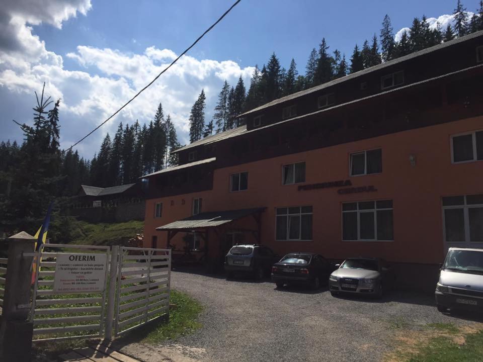 ein Gebäude mit davor geparkten Autos in der Unterkunft Pensiunea Cerbul in Lacul Roşu