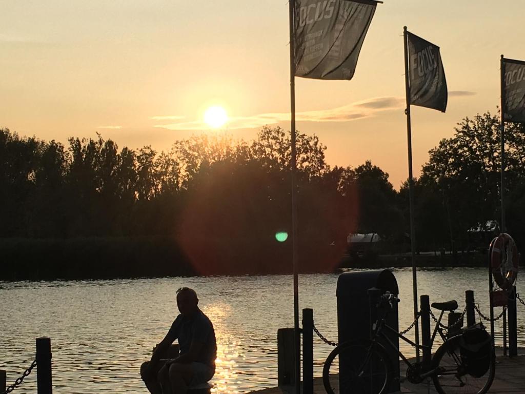 バラトンギュルクにあるAndre & Moniの旗を掲げた水の横に座る男