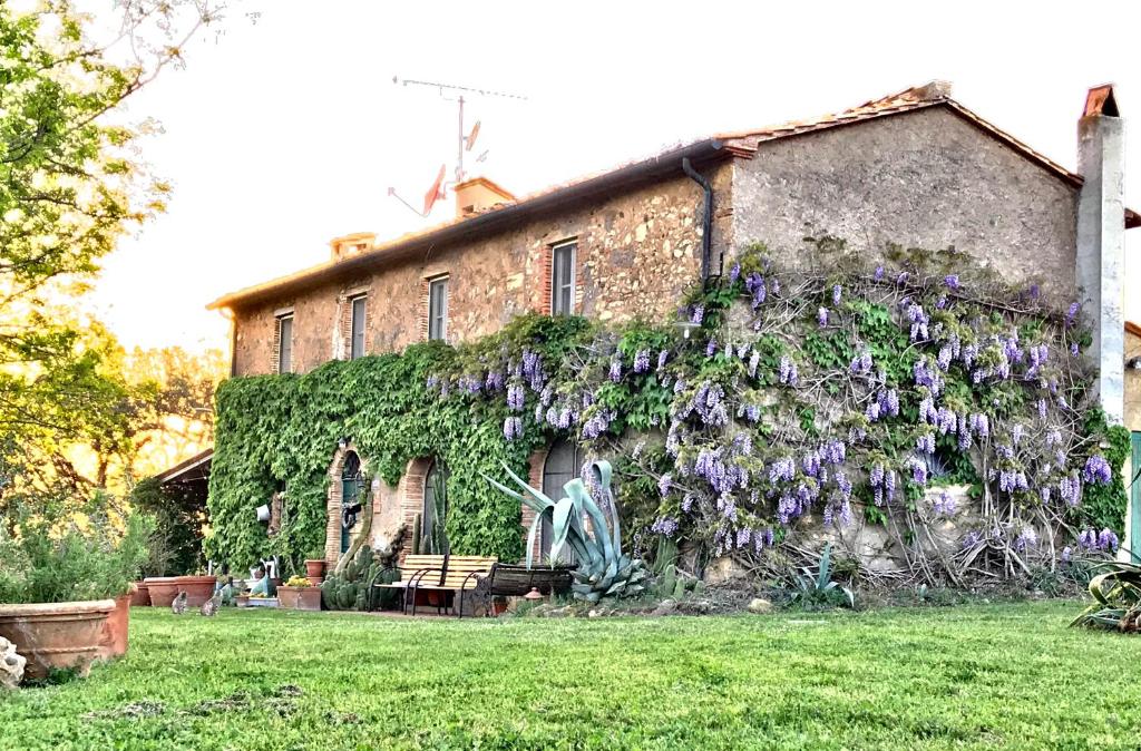un edificio con flores púrpuras a su lado en Agriturismo La Leccia, en Bibbona