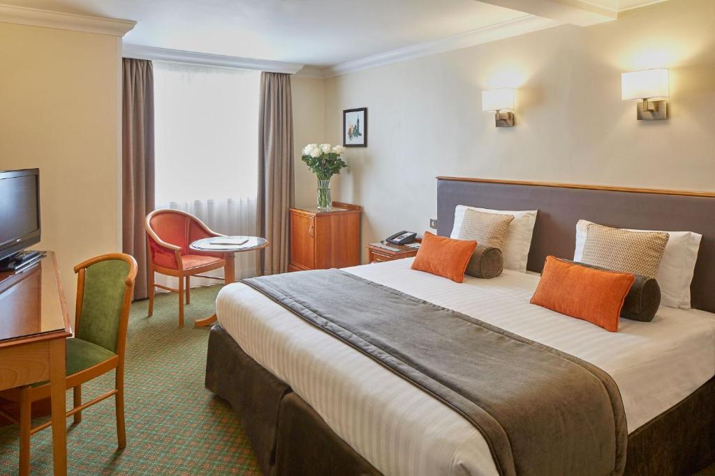 ロンドンにあるランカスター ゲイト ホテルのベッドとテレビが備わるホテルルームです。