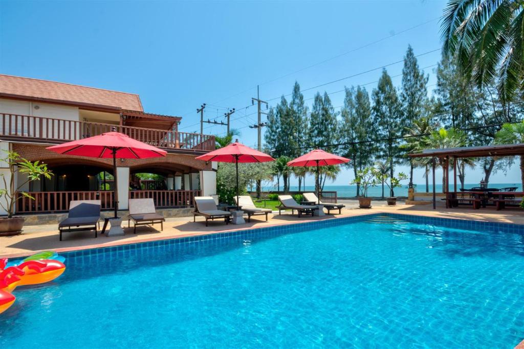 a swimming pool with chairs and umbrellas at Palm Beach Resort in Pran Buri