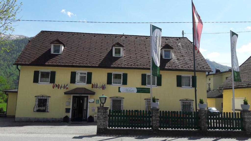 a yellow building with a fence in front of it at Frühstückspension Haus Ahamer in Ebensee