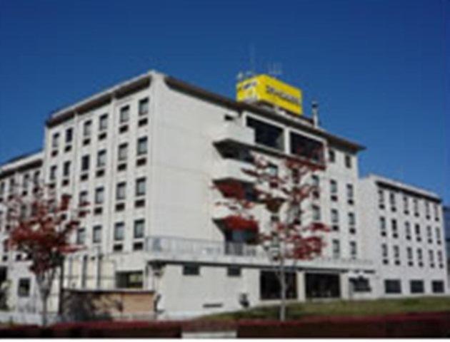 a white building with a yellow sign on top of it at Smile Hotel Koriyama in Koriyama