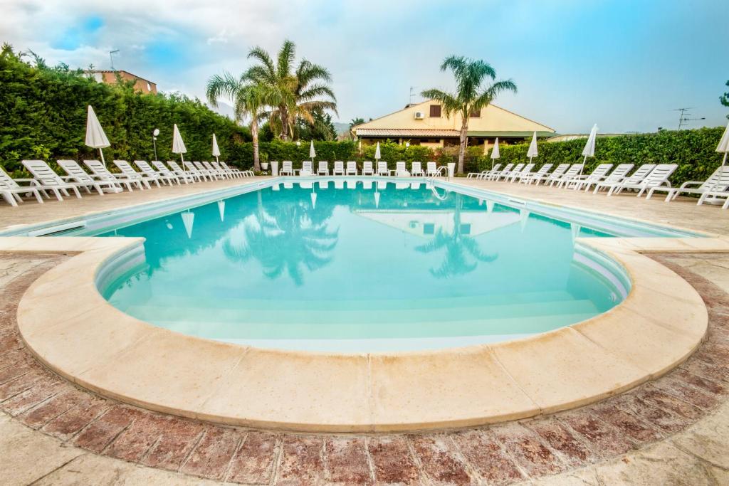 a large swimming pool with chairs and a resort at Paradise Beach camera mansardata vicino Cefalù PISCINA APERTA in Campofelice di Roccella