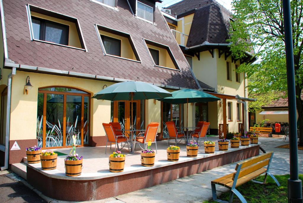 a row of chairs and umbrellas in front of a building at Hotel Flóra** in Orosháza