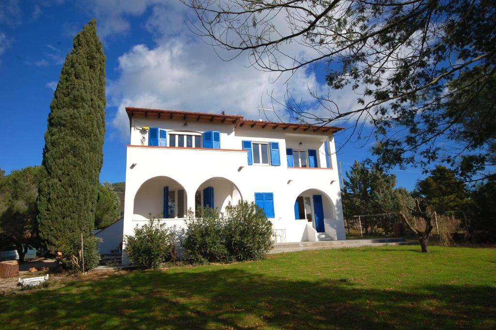 Casa blanca con ventanas azules y patio en Casa Balena Bianca en Lacona