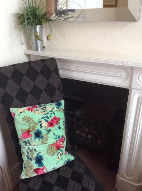 a chair with a pillow sitting next to a fireplace at Cheltenham Lawn and Pittvile Gallery in Cheltenham