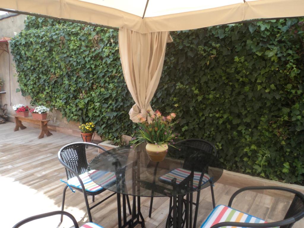 un tavolo con sedie e un ombrellone davanti ad una siepe di Casa en Alcalá del Jucar a Casas del Cerro