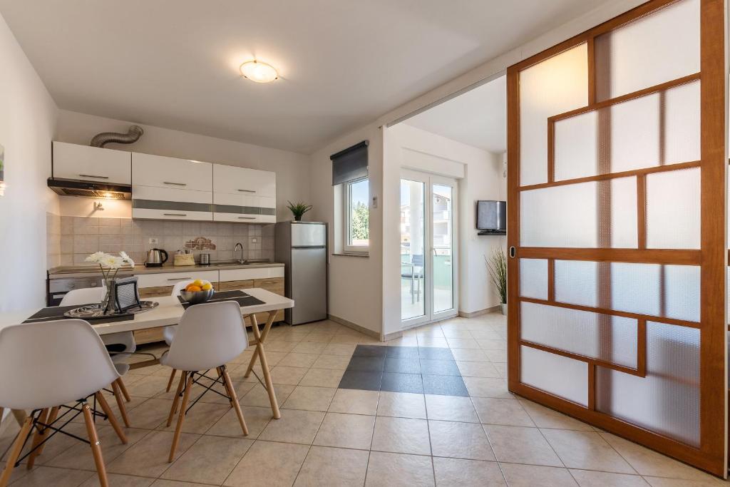 een keuken met witte kasten en een tafel en stoelen bij Apartment Vivis in Medulin