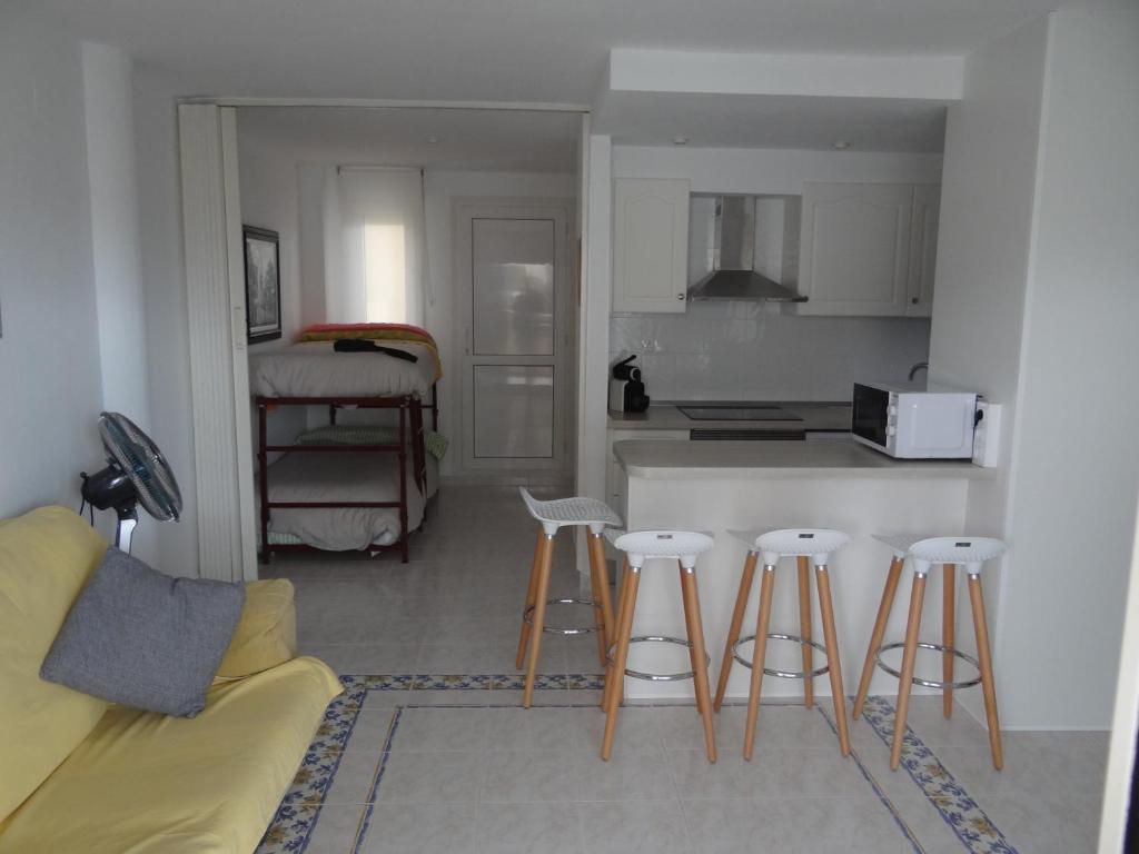 a kitchen with four bar stools in front of a counter at Apartamento en Vinaros in Vinaròs