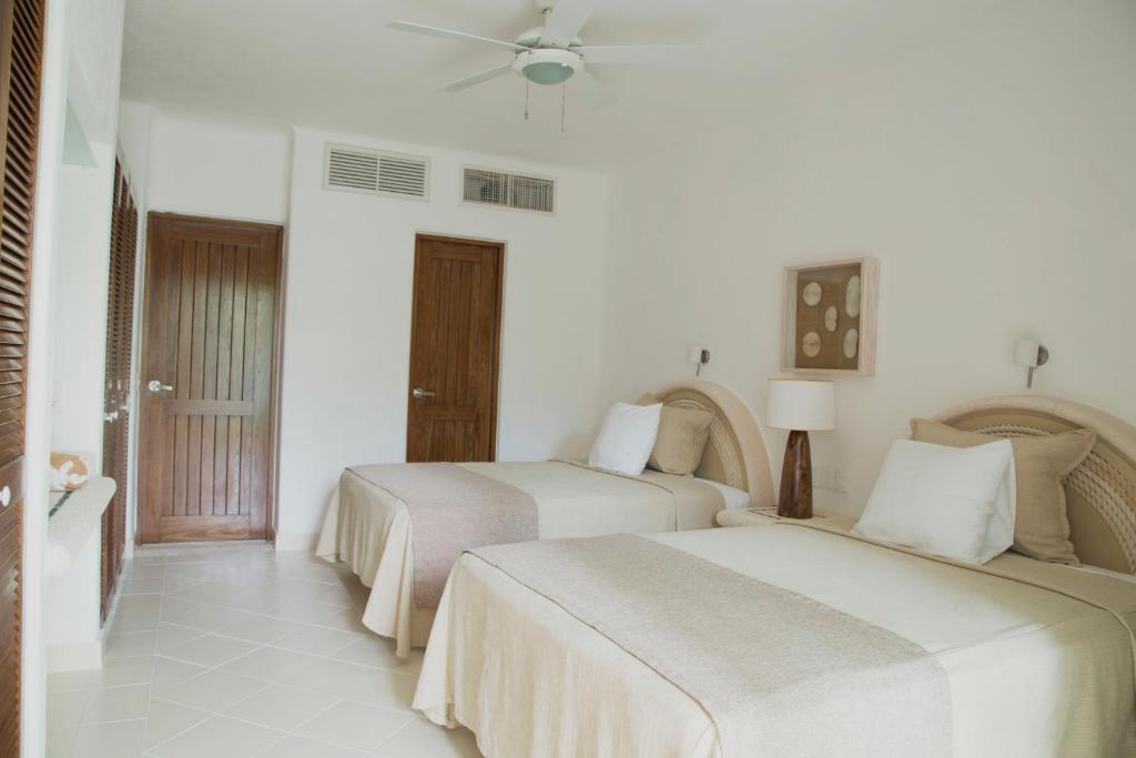 two beds in a room with white walls at Las Villas Akumal in Akumal