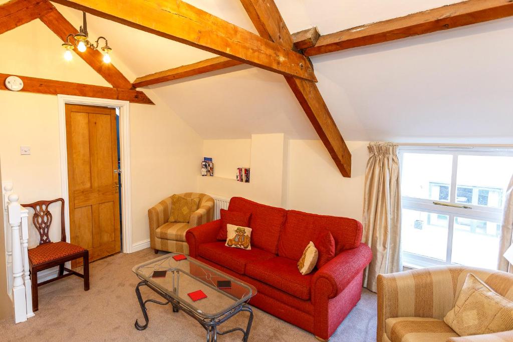 a living room with a red couch and a glass table at The Hay Loft in Sedgefield