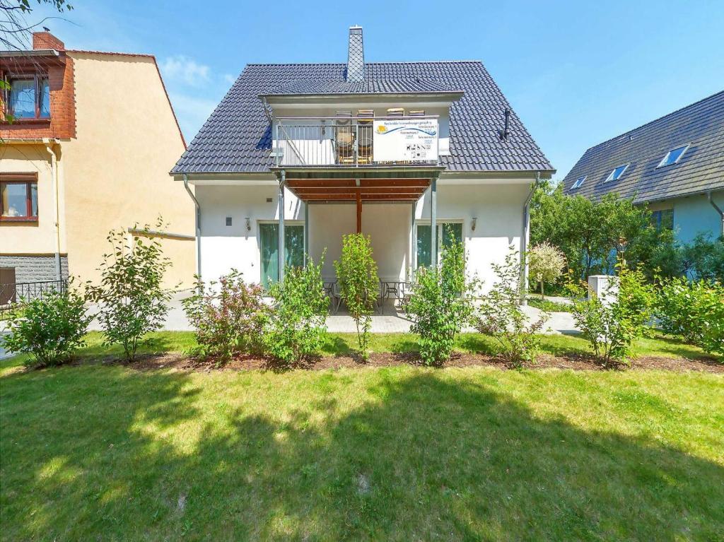 een wit huis met een balkon in een tuin bij Haus Werder Wohnung 3 mit Kamin in Zinnowitz
