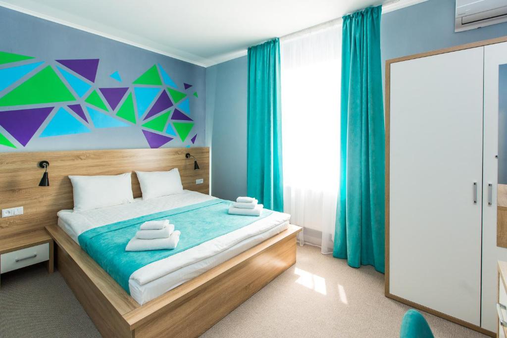 リヴィウにあるBlum Hotelの青と緑の壁のベッド1台が備わるベッドルーム1室が備わります。