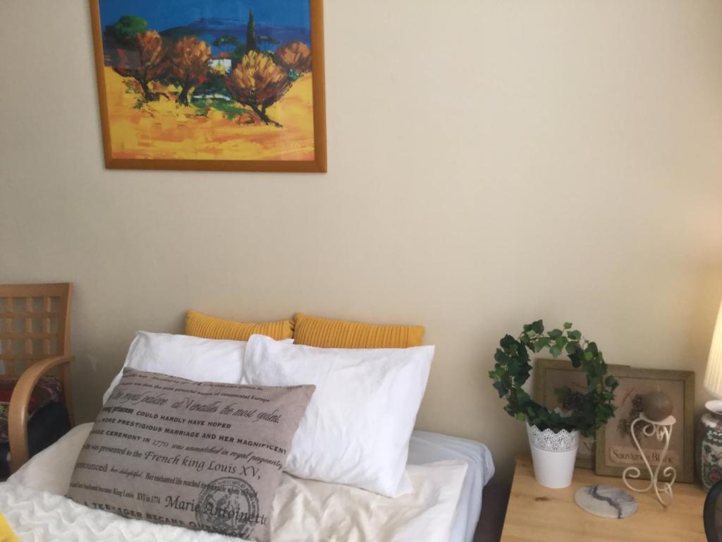 a bed with white sheets and a painting on the wall at Sharm Sweet Studio 49 City Center Kamppi in Helsinki